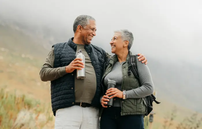 Older couple drinking while on a hike and smiling for some reason