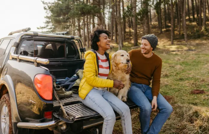 couple with dog sitting on open tailgate of truck